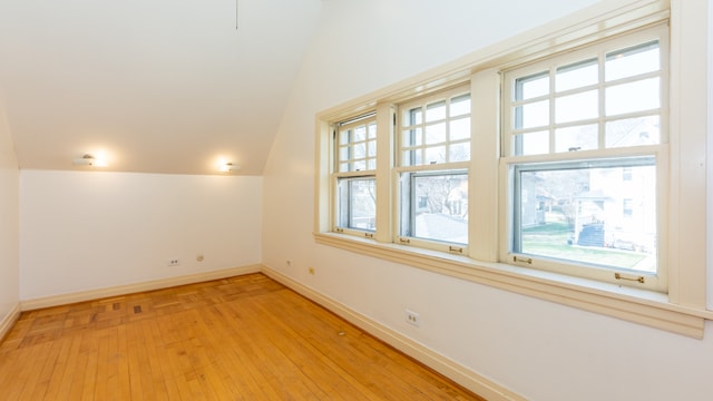 additional living space featuring vaulted ceiling and light hardwood / wood-style flooring