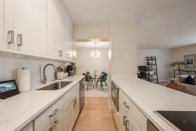 kitchen with light hardwood / wood-style floors, light stone countertops, sink, and pendant lighting