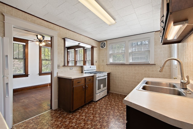 kitchen with dark brown cabinets, dark hardwood / wood-style flooring, tile walls, sink, and white appliances