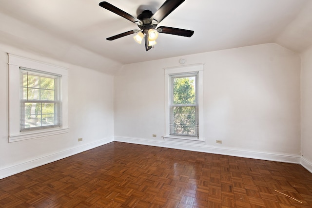 empty room featuring lofted ceiling, dark parquet floors, and ceiling fan