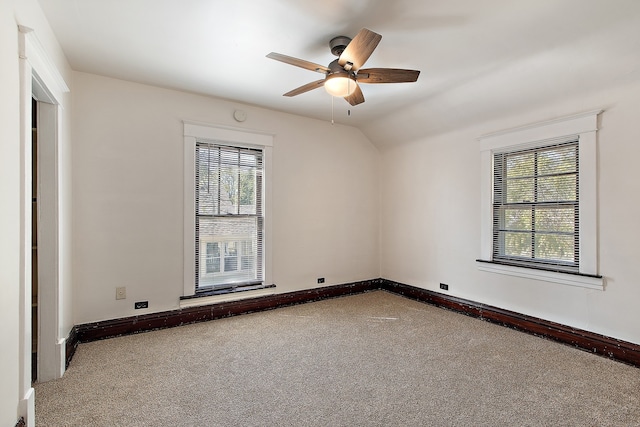 empty room featuring vaulted ceiling, carpet flooring, plenty of natural light, and ceiling fan