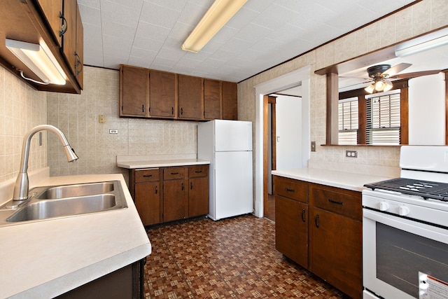 kitchen featuring white appliances, ceiling fan, tile walls, and sink