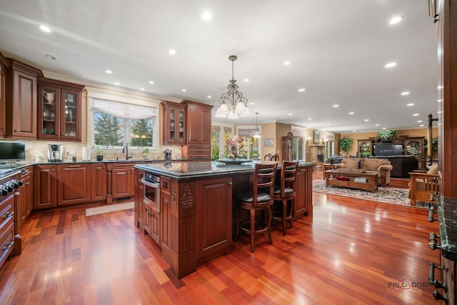 kitchen featuring a kitchen bar, dark hardwood / wood-style flooring, a chandelier, a kitchen island, and hanging light fixtures