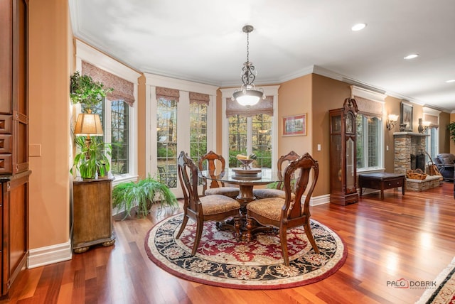 dining room with a stone fireplace, crown molding, and dark wood-type flooring