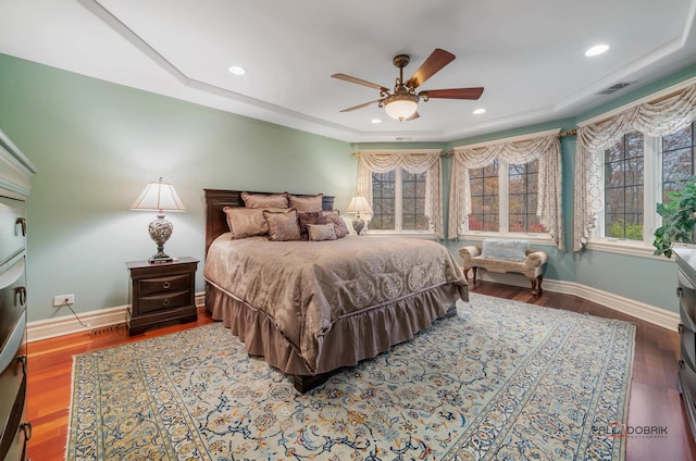 bedroom featuring a raised ceiling, ceiling fan, and hardwood / wood-style floors