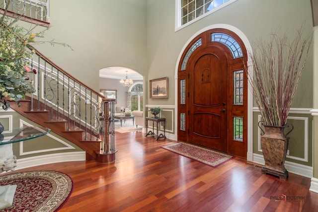 entrance foyer featuring a chandelier, wood-type flooring, and a high ceiling