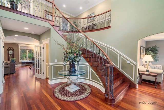 stairway featuring hardwood / wood-style floors, a towering ceiling, french doors, and crown molding