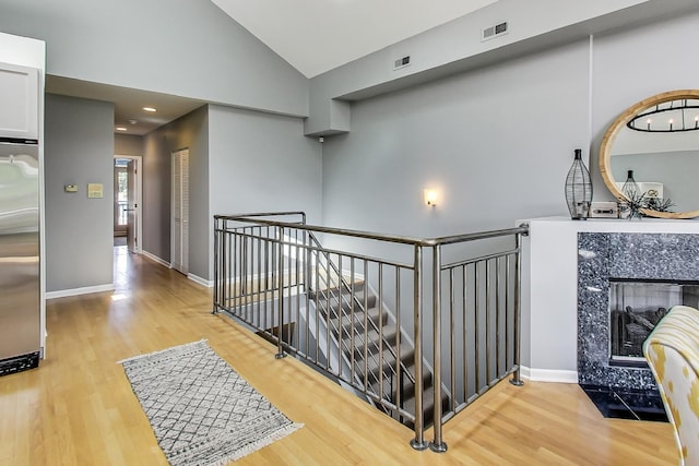 hall with lofted ceiling and light wood-type flooring