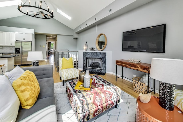 living room featuring a fireplace, high vaulted ceiling, and a chandelier