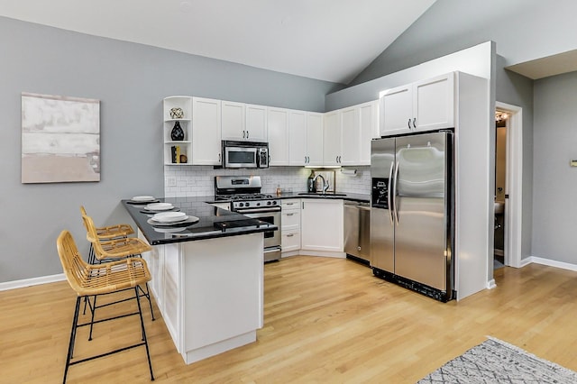 kitchen with white cabinetry, appliances with stainless steel finishes, a breakfast bar, and kitchen peninsula