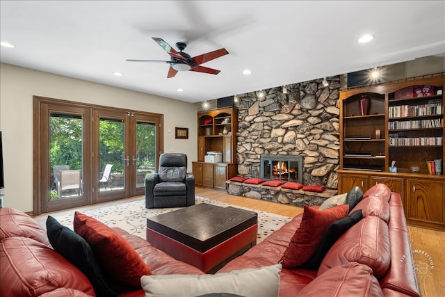 living room with a fireplace, light wood-type flooring, and ceiling fan