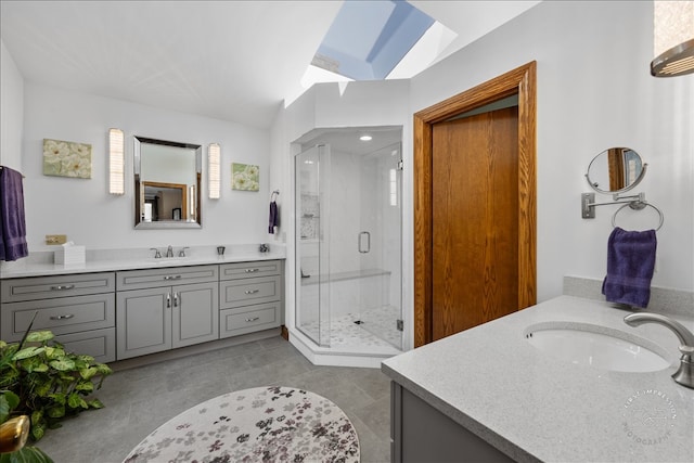 bathroom featuring a shower with door, vanity, lofted ceiling with skylight, and tile patterned flooring