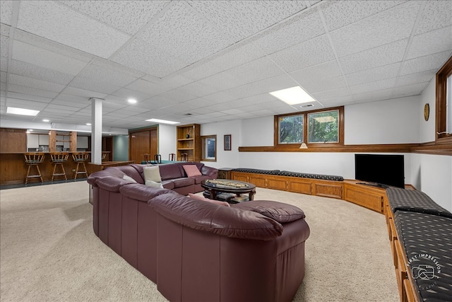 carpeted living room with a drop ceiling and bar