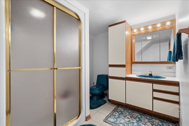 bathroom with vanity, toilet, a shower with shower door, and tile patterned floors