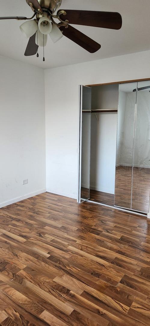 unfurnished bedroom featuring ceiling fan, dark hardwood / wood-style floors, and a closet