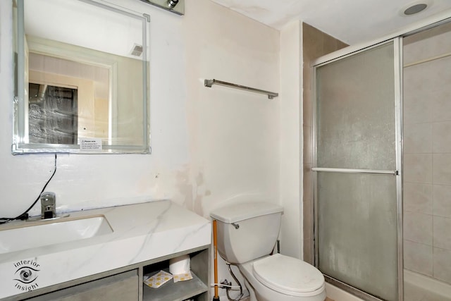 bathroom featuring vanity, toilet, and a shower with shower door