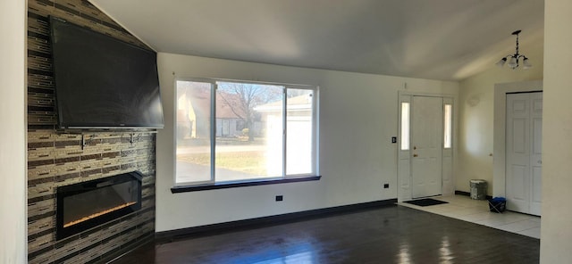 unfurnished living room with a chandelier, a fireplace, light hardwood / wood-style floors, and lofted ceiling