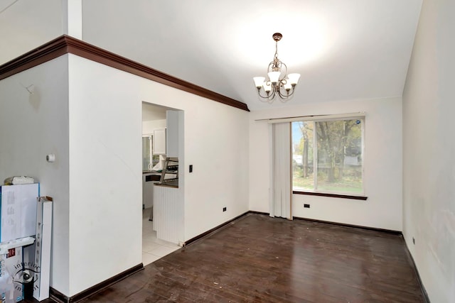 empty room with a chandelier, wood-type flooring, and lofted ceiling