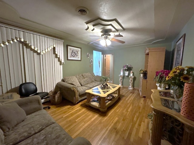 living room featuring a textured ceiling, light wood-type flooring, and ceiling fan