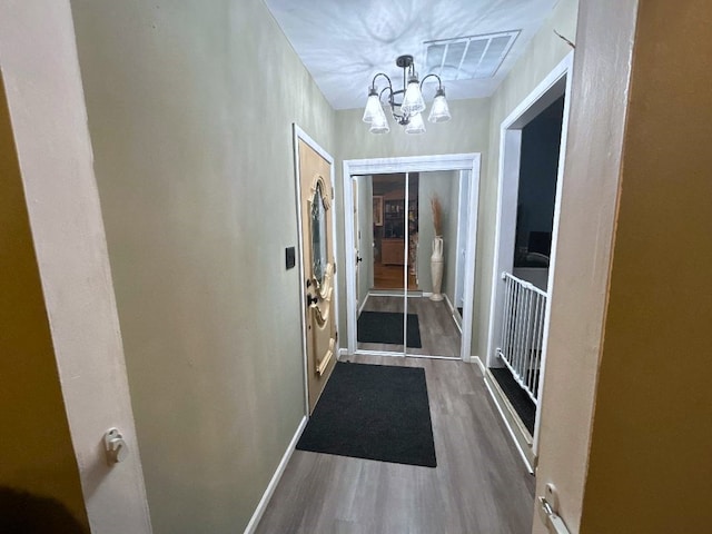 doorway to outside with a notable chandelier and dark hardwood / wood-style floors