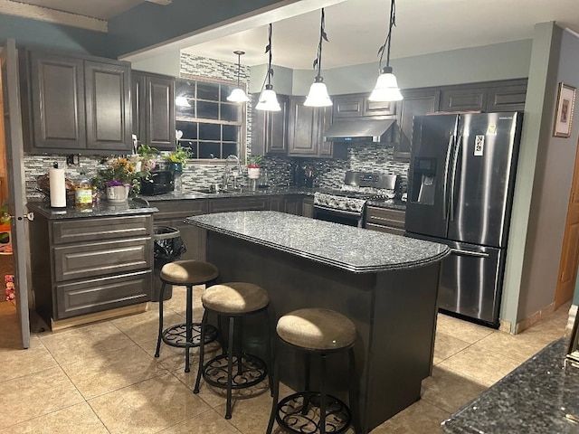 kitchen with a kitchen breakfast bar, stainless steel appliances, sink, a center island, and tasteful backsplash