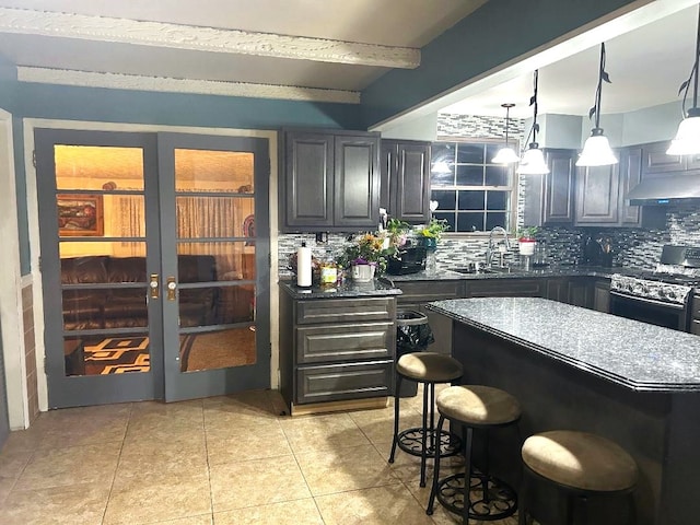 bar with sink, black range with electric stovetop, beamed ceiling, pendant lighting, and decorative backsplash