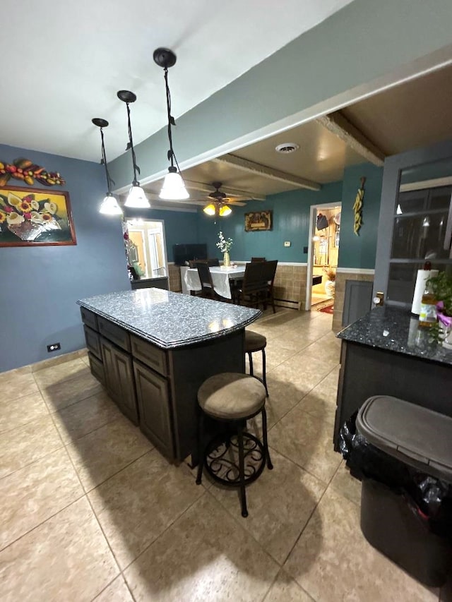 kitchen featuring dark stone countertops, dark brown cabinetry, beamed ceiling, and pendant lighting