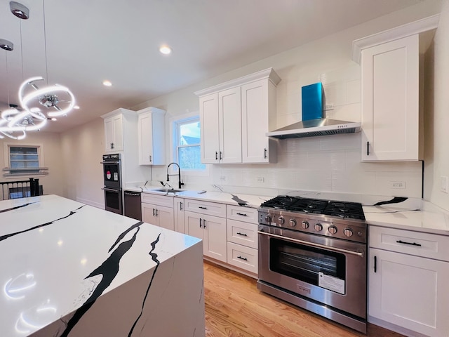 kitchen featuring white cabinetry, sink, wall chimney exhaust hood, stainless steel appliances, and pendant lighting