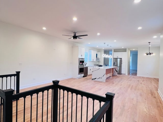 living room with ceiling fan with notable chandelier and light wood-type flooring