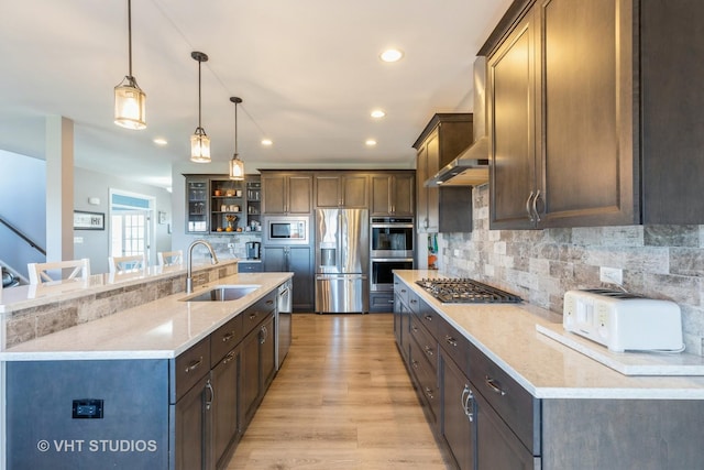 kitchen featuring a large island, stainless steel appliances, decorative light fixtures, and sink