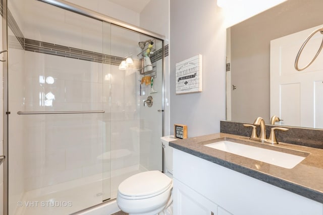 bathroom with vanity, a shower with door, and toilet