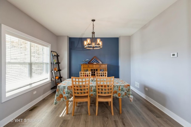 dining room with dark wood-type flooring and a notable chandelier