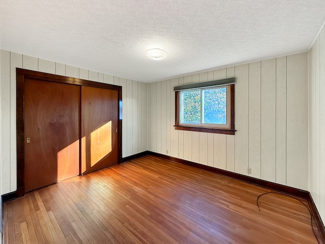 unfurnished bedroom with wood-type flooring, a textured ceiling, and a closet