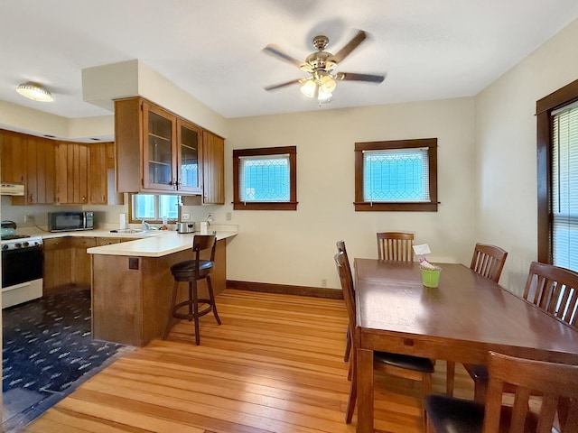103 E Roosevelt St, Freeport, IL 61032 - kitchen with white gas stove, brown cabinets, light wood finished floors, light countertops, and a kitchen breakfast bar