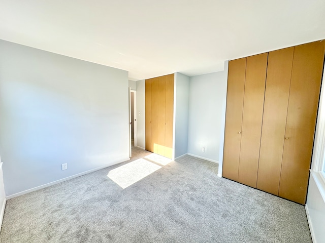 unfurnished bedroom featuring a closet and light carpet