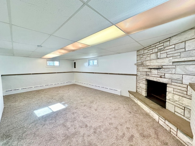 basement with a drop ceiling, a baseboard heating unit, and carpet