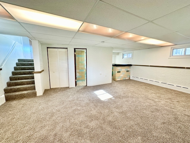 basement with a baseboard radiator, carpet, and a drop ceiling