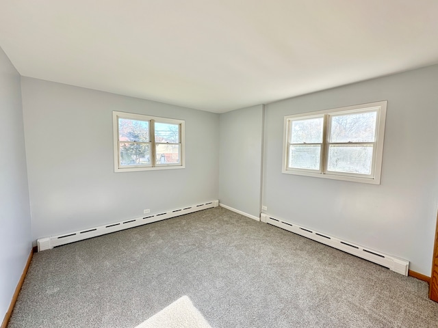 carpeted spare room with baseboard heating and plenty of natural light