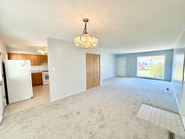 carpeted empty room featuring ceiling fan with notable chandelier