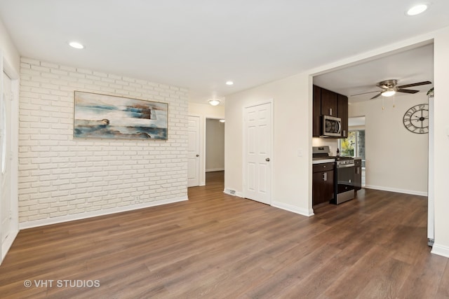 living room with dark hardwood / wood-style flooring, ceiling fan, and brick wall