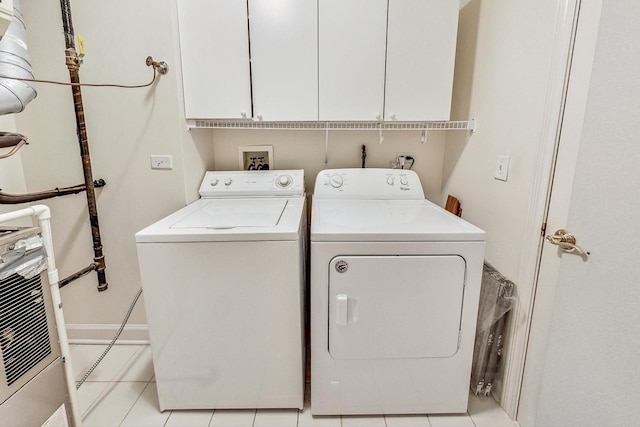 clothes washing area featuring cabinets, light tile patterned floors, and washer and dryer