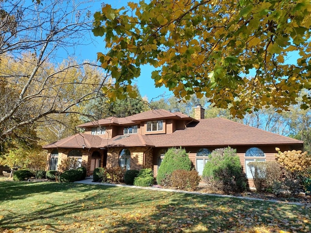 view of front of house featuring a front lawn, a chimney, and a shingled roof