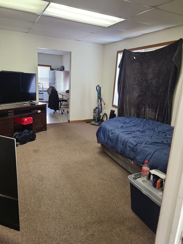 carpeted bedroom featuring a drop ceiling and white refrigerator