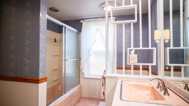 bathroom with vanity, a healthy amount of sunlight, and bath / shower combo with glass door