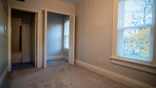 unfurnished bedroom with multiple windows, a closet, and carpet flooring