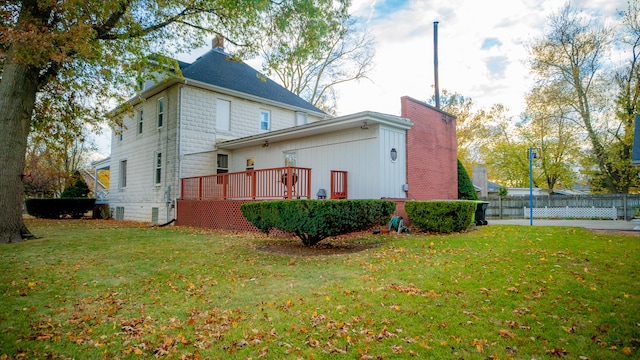 view of side of home with a deck and a yard