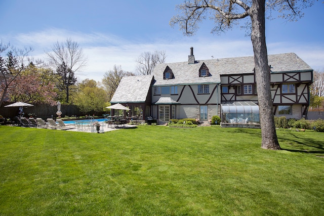 back of property with a fenced in pool, a patio area, and a yard