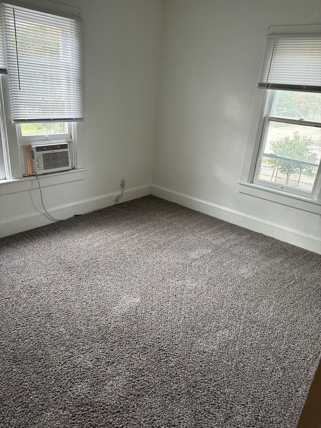 carpeted empty room featuring cooling unit and plenty of natural light