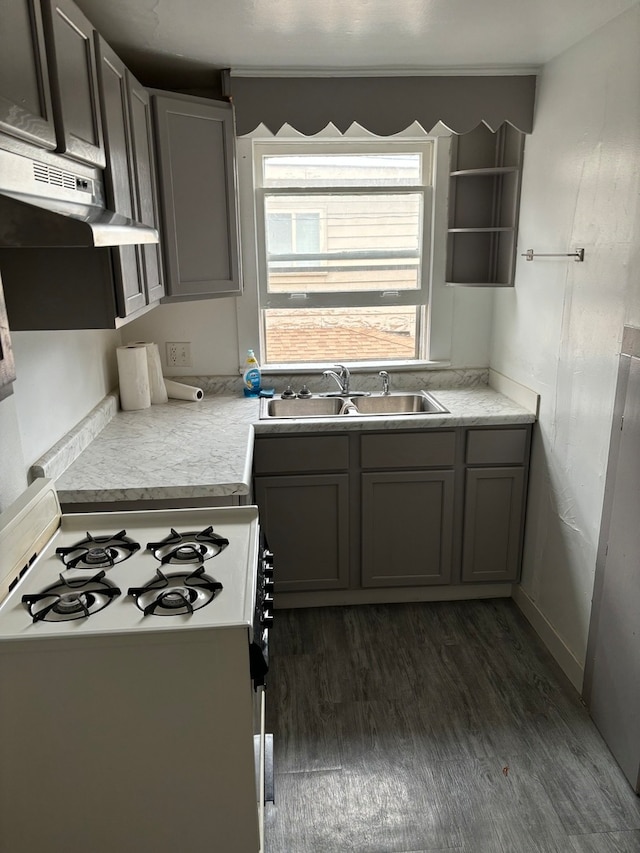 kitchen featuring dark hardwood / wood-style floors, extractor fan, gray cabinetry, sink, and white range with gas stovetop