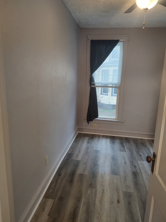 unfurnished room featuring a textured ceiling, ceiling fan, and dark hardwood / wood-style flooring